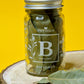 Dried bay leaves in a clear glass jar, displaying vibrant green color and rich texture, commonly used for seasoning soups, stews, and sauces.