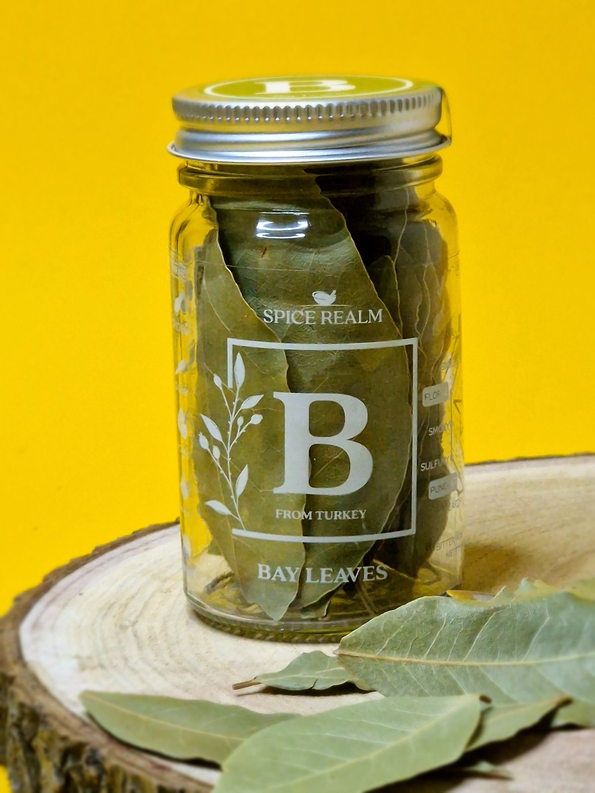 Dried bay leaves in a clear glass jar, displaying vibrant green color and rich texture, commonly used for seasoning soups, stews, and sauces.