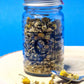 Jar of dried organic Chamomile Flowers, showcasing their small, daisy-like appearance and pale yellow colour