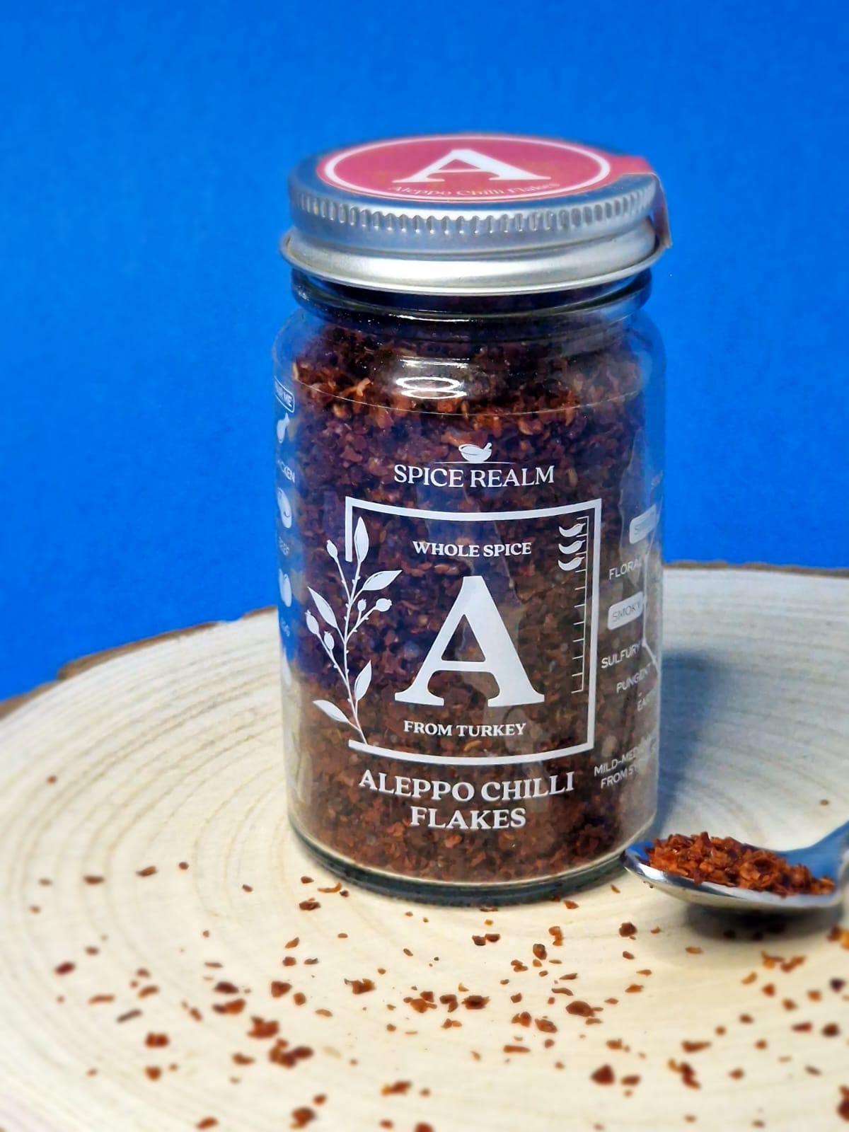 Close-up image of vibrant red Aleppo chilli flakes, showcasing their coarse texture and deep red hue, perfect for adding a mild heat and fruity flavour to a variety of dishes