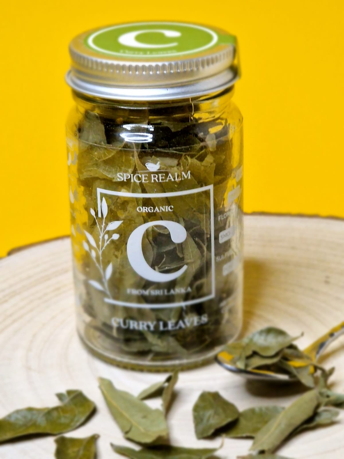 Jar of dried organic Curry Leaves, showing their small, oval shape and deep green colour