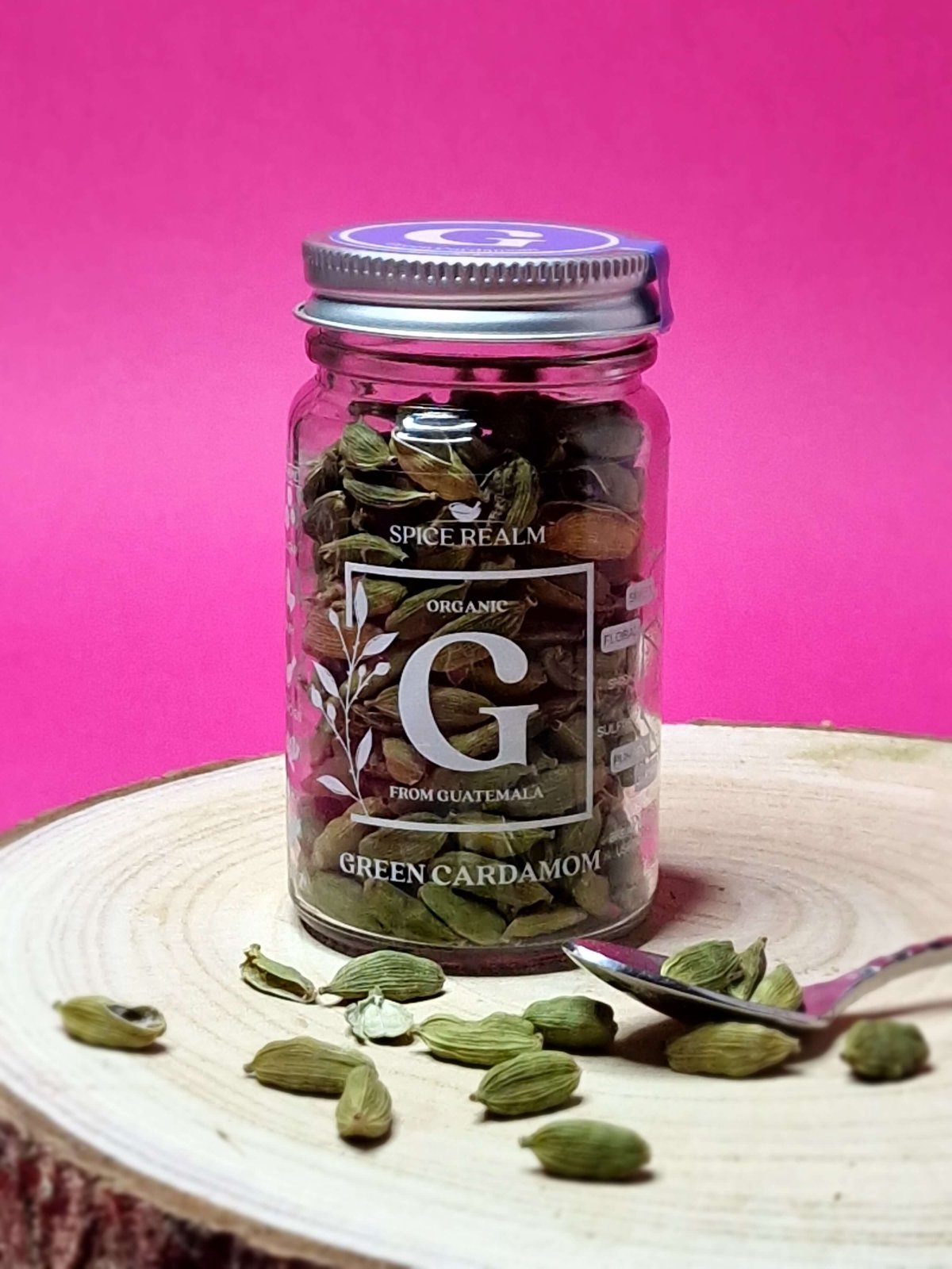 Jar of whole organic Green Cardamom pods, showcasing their small, oval shape and light green colour